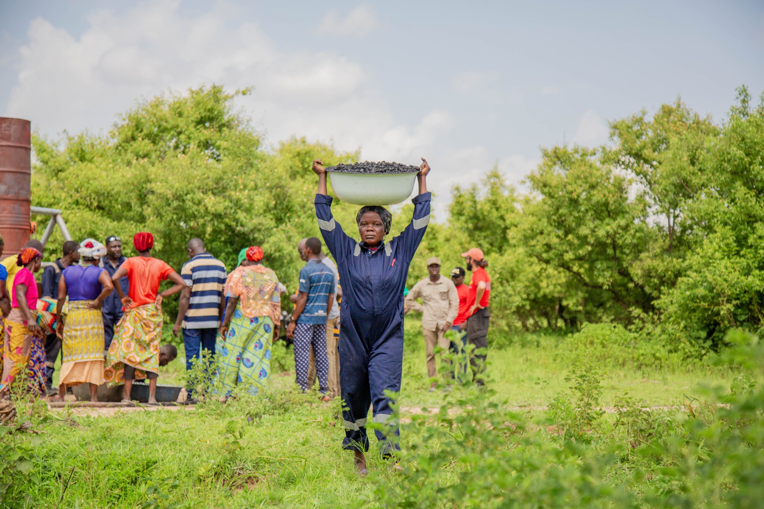 A farmer carrying a bowl of freshly made biochar on her head